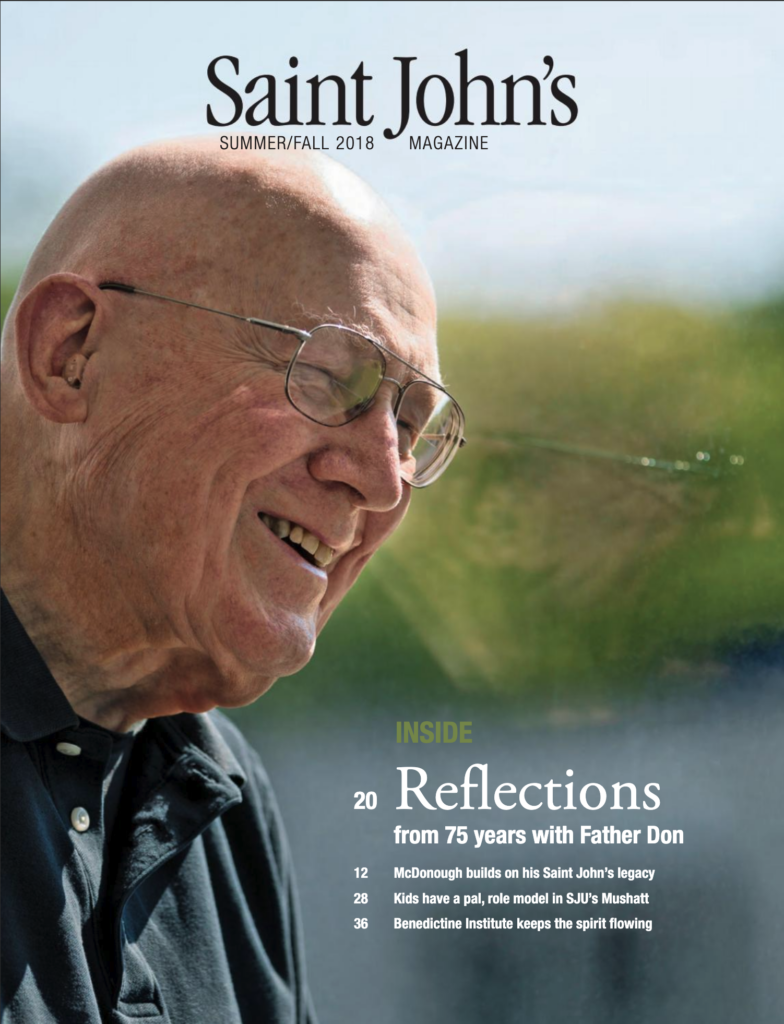 An elderly man with glasses and a bald head smiles warmly in an outdoor setting. He wears a black polo shirt. The magazine cover features the title "Saint John's" and headlines about reflections, legacy, and spiritual guidance.